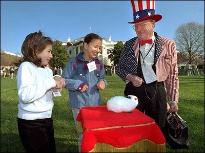 Hopping from activity to activity, two girls stop to pet a real Easter bunny on the South Lawn, April 1, 2002, during the White House Easter Egg Roll.