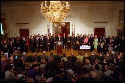 Joined by members of Congress and 15 American families in the East Room June 7, 2001, President George W. Bush signs the Tax Relief Act, which provides Americans with across-the-board tax cuts.