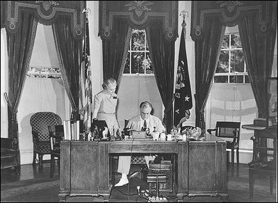 While working at his desk in the Oval Office, which he had moved to its current location in 1934, President Franklin Roosevelt meets with Marguerite Le Hand, his personal secretary.