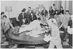 Reporters jump over tables in the White House to pick up press releases about the Japanese surrender, August 14, 1945.