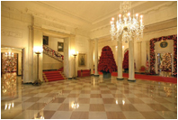 Entrances to both the East Room and the State Dining Room from the Cross Hall are surrounded by garlands full of large pine cones, red glass balls, red icicles and red pepper berries.