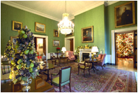 One of the finest pieces of art in the White House, the portrait of Benjamin Franklin by David Martin, is the centerpiece of the Green Room. Topiaries of gold and green fruit stand on either side of the sofa and brilliant red poinsettias and fresh green pears.