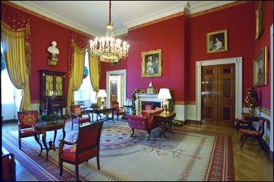The Red Room is decorated with garlands and topiaries made of pomegranates, pears and magnolia leaves. A small cranberry tree surrounded by holly sits on an antique marble-top table.
