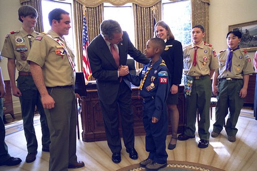 President George W. Bush talks with Jordon Wade, 9, of Pittsburgh during the presentation of the annual report by the Boy Scouts of America in the Oval Office Feb. 12, 2002. Other scouts included in the ceremony are, from left to right, Joe Honious, 16, of Dayton, Ohio; Clay Capp, 18, of Nashville, Tenn.; national Venturing President Marissa Morgan, 19, of Winston-Salem, NC; Joshua Cudd, 12, of Conroe, Texas; and Ryan Iwata, 12, of San Francisco. Not pictured is David Richey, 18, of Seattle, Wash. White House photo by Eric Draper.