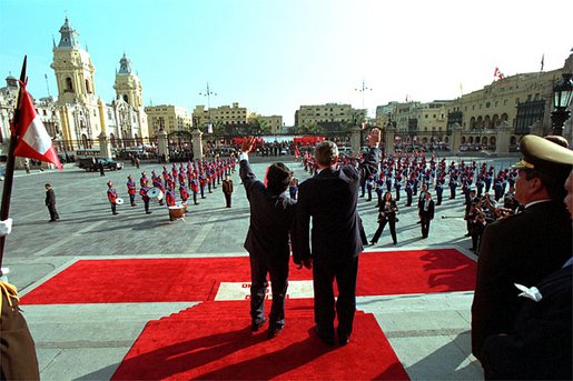 President George W. Bush and Peruvian President Alejandro Toledo (right) wave from the steps of the Presidential Palace in Lima, Peru, March 23. "This is an historic visit made by a friend representing a country with which we have had an historical relationship," said President Toledo. "It is not merely a diplomatic visit, it is an official working visit and we have touched on substantive issues, which range from the open struggle against poverty, a war without quarter against terrorism and drug trafficking." White House photo by Eric Draper.