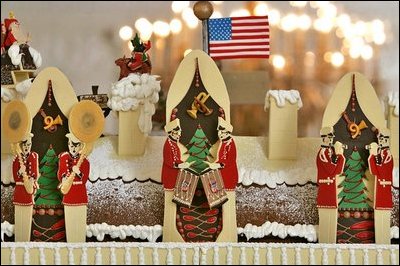 The roof of the White House Gingerbread House is adorned with Santa Claus, his sleigh, and a trio of instruments. The American Flag sits prominently on the roof.