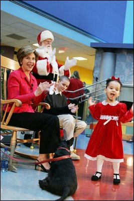 Mrs. Bush and Taylor Buckles, older sister of conjoined twins successfully separated earlier this year, react to the first viewing of the 2004 BarneyCam during a children's holiday program at the Children's National Medical Center in Washington, D.C., Wednesday, Dec., 15, 2004. 