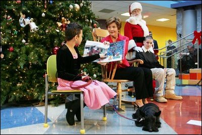 Mrs. Bush reads "Dream Snow" by Eric Carle with help from her patient escorts, Brandy Robinson, left, and Keith "Koddie" Hernandez during the annual Children's National Medical Center holiday program in Washington, D.C., Wednesday, Dec. 15, 2004. 