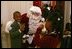 School children attending the White House Children's Christmas Program offer cookies to Santa Claus in the East Room Dec. 6, 2004. 