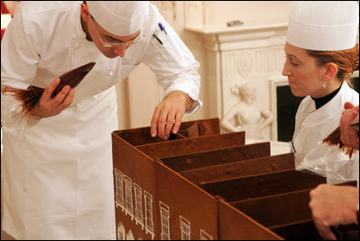 Head Pastry Chef Thaddeus DuBois and assistant Suzie Morrison glue together the foundation of the official White House gingerbread house using chocolate as the glue.