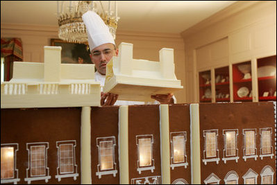 Thaddeus DuBois, Head Pastry Chef, places the roof on top of the White House gingerbread house.
