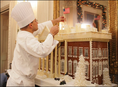 White House pastry chef Thaddeus DuBois tops off his gingerbread house with a flag, Wednesday, Nov. 30, 2005, in the State Dining Room, as the finishing touches are made to the White House Christmas decorations.