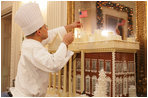 White House pastry chef Thaddeus DuBois tops off his gingerbread house with a flag, Wednesday, Nov. 30, 2005, in the State Dining Room, as the finishing touches are made to the White House Christmas decorations.