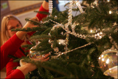 Decorators place holiday trimmings on the White House Christmas Tree, a large Fraser Fir, in the Blue Room of the White House, Tuesday, Nov. 29, 2005.