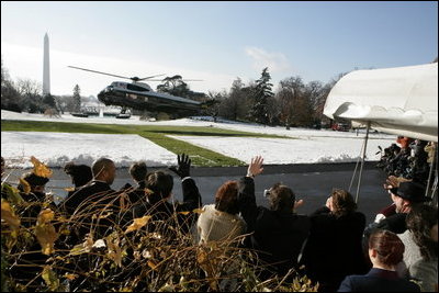 Visitors wave as President Bush takes off in Marine One from a snow-covered South Lawn Friday, Dec. 9, 2005.