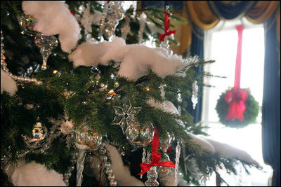 The White House Christmas tree in the Blue Room is adorned with crystals, iridescent glass ornaments fastened to the tree with red satin bows and topped off with soft, cotton snow.