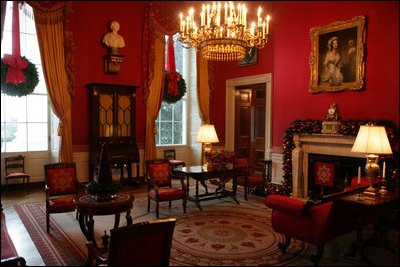 The mantle in the Red Room is draped with garland and entwined with gold etched ornaments. Twin evergreen wreaths decorate the windows. The miniature cranberry tree is a White House tradition dating back to 1975.