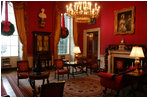 The mantle in the Red Room is draped with garland and entwined with gold etched ornaments. Twin evergreen wreaths decorate the windows. The miniature cranberry tree is a White House tradition dating back to 1975.
