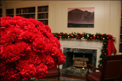 Red carnations in silver containers bloom as the centerpiece of the White House Library.
