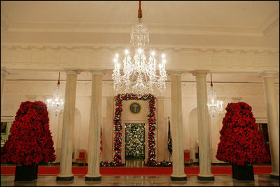 Trees sculpted from poinsettias line the Cross Hall. The White House Christmas tree fills the Blue Room doorway with lights and snow dappled branches. White House decorators used 4,638 red color ornament balls in their festive adornments.