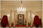 Trees sculpted from poinsettias line the Cross Hall. The White House Christmas tree fills the Blue Room doorway with lights and snow dappled branches. White House decorators used 4,638 red color ornament balls in their festive adornments.
