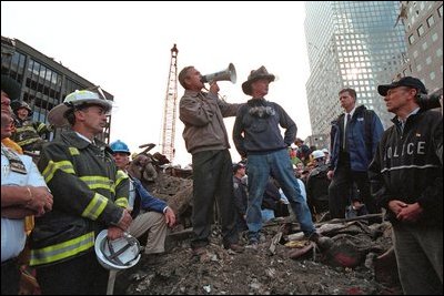 Standing on top of a crumpled fire truck with retired New York City firefighter Bob Beckwith, President George W. Bush rallies firefighters and rescue workers during an impromptu speech at the site of the collapsed World Trade Center towers Sept. 14, 2001. "I can hear you," President Bush said. "The rest of the world hears you. And the people who knocked these buildings down will hear all of us soon." 
