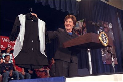Laura Bush displays a school uniform to the press at Samuel W. Tucker Elementary School in Alexandria, Va., March 20, 2002. “A group of people from around the globe have gotten together to raise the money to send manual sewing machines to Afghanistan, so women can have jobs making uniforms. And when girls go back to school in a few weeks, they’ll have a uniform to wear to school,” explained Mrs. Bush to the press.