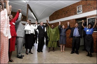 President George W. Bush, Mrs. Laura Bush, and to the President's right, Ugandan President Yoweri Museveni and Mrs. Museveni sing along with a choir and staff members of The AIDS Support Organization (TASO) Centre in Entebbe, Uganda Friday, July 11, 2003. White House photo by Susan Sterner