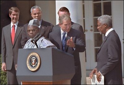 President George W. Bush welcomes UN Secretary General Kofi Annan to the podium after his announcement of Presidential HIV/AIDS Trust Fund Initiative as Nigerian President Olusegun Obsanjo looks on at left in the Rose Garden, Friday, May 11, 2001.
