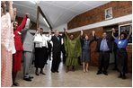President George W. Bush, Mrs. Laura Bush, and to the President's right, Ugandan President Yoweri Museveni and Mrs. Museveni sing along with a choir and staff members of The AIDS Support Organization (TASO) Centre in Entebbe, Uganda Friday, July 11, 2003.