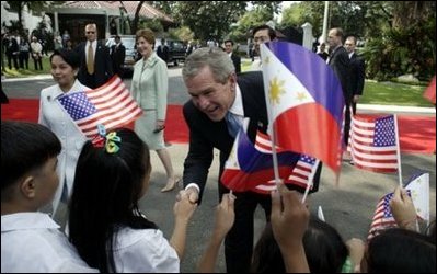 President George W. Bush greets school children during a welcoming ceremony at Malacanang Palace in Manila, The Philippines along with Philippine president Gloria Arroyo and Mrs. Laura Bush on Saturday October 18, 2003. White House photo by Paul Morse