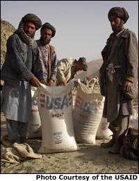 Photo of Afghan men standing with a bag of wheat marked with USA. Photo Courtesy of the USAID
