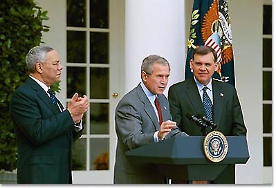 President George W. Bush discusses America's policies regarding Cuba as Secretary of State Colin Powell, left, and Secretary of Housing and Urban Development Mel Martinez stand by his side in the Rose Garden Friday, Oct. 10,