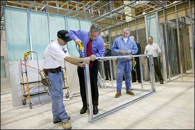 President George W. Bush uses a drill to connect a metal wall frame during a tour of the Carpenters Training Center in Phoenix, Ariz., March 26, 2004.