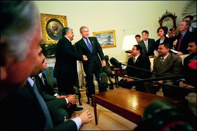 President George W. Bush talks with Iraqis whose right hands were amputated under the regime of Saddam Hussein during a visit to the Oval, Office May 25, 2004. The attendees had received medical attention in the United States.