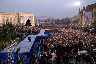 Standing with Romanian President Iliescu, President George W. Bush waves to thousands of Romanians in Revolution Square in Bucharest, Romania, Nov. 23, 2002. The square is the site of the 1989 revolt that toppled communist rule and where the Romanian people denounced the dictator Nicolae Ceausescu. 'And here, in December of 1989, you broke the silence of your captivity,' remarked President Bush. 'From that balcony, the dictator heard your voices and faltered -- and fled. Two generations of bitter tyranny ended, and all the world witnessed the courage of Romania, the courage that set you free.' White House photo by Paul Morse 