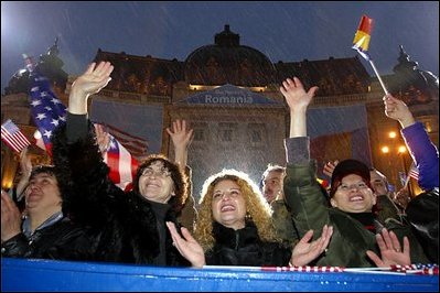 Braving a cold rain, thousands of Romanian citizens came to Revolution Square to hear President Bush speak Nov. 23, 2002. 'I know that your hardship did not end with your oppression. America respects your labor, your patience, your daily determination to find a better life. Your effort has been recognized by an offer to NATO membership. We welcome Romania into NATO,' said President Bush. White House photo by Paul Morse