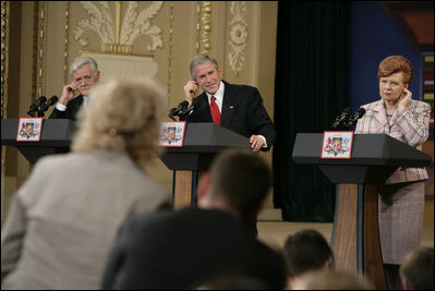 From left, Lithuanian President Valdas Adamkus, President George W. Bush and Latvia President Vaira Vike-Freiberga adjust their earphones to hear interpreters during a question and answer session Saturday, May 7, 2005, in Riga, Latvia.