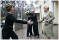 President George W. Bush and Russia President Vladimir Putin embrace in the background as Mrs. Bush reaches out to Ludmila Putina, Russia's first lady, as the Bushes arrived Sunday, May 8, 2005, at the Putin residence shortly after their arrival in Moscow.