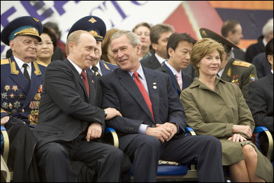 President George W. Bush and Russian President Vladimir Putin share a light moment as they sit with Laura Bush and other heads of state during a military parade marking the end of World War II in Moscow's Red Square, Monday, May 9, 2005.