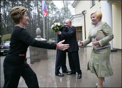 President George W. Bush and Russia President Vladimir Putin embrace in the background as Mrs. Bush reaches out to Ludmila Putina, Russia's first lady, as the Bushes arrived Sunday, May 8, 2005, at the Putin residence shortly after their arrival in Moscow.