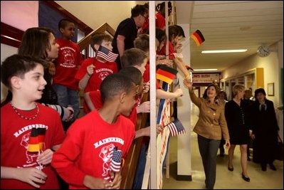 Laura Bush reaches for the hands of children waving U.S. and German flags as she passes them in the hallway of the Hainerberg Elementary School February, 22, 2005, in Wiesbaden, Germany.