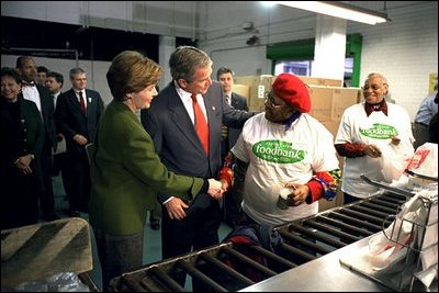 President George W. Bush and Laura Bush help volunteers pack food during their visit to the Capital Area Food Bank in Washington, D.C., Thursday, Dec. 19. "More Americans need to volunteer. There are ways to do so. The USAFreedomCorps.gov on the web page is the place to look," said the President in his remarks. "You can call 1-877-USA-CORPS and find out ways that you can help. If you are interested in being a part of feeding those who hunger, this is a great place to come to." 