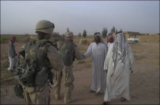 Iraqi men greet soldiers from the 422nd Civil Affairs Battalion.