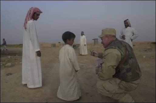 Lt. Col. Alan King of the 422nd Civil Affairs Battalion rewards the warm welcome he received from an Iraqi boy with some sweets.