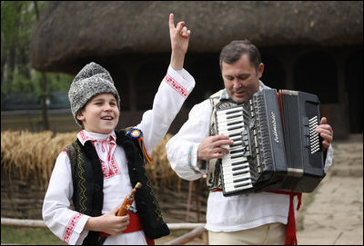 A young boy sings and dances as he's accompanied by an accordionist during a performance for the official NATO Spouses' Program Thursday, April 3, 2008, at the Dimitrie Gusti Village Museum in Bucharest.