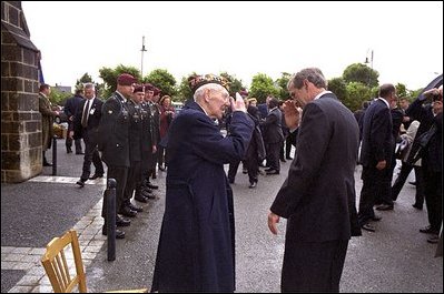 President George W. Bush salutes a veteran during a Memorial Day service at Notre Dame De La Paix Church at Normandy, France, May 27, 2002. The President and Mrs. Bush visited the beach and an American ceremony in honor of D-Day veterans. 
