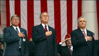 President George W. Bush watches the posting of colors with Joe Burns, National President of Blinded Veterans of America, left, and Anthony Principi, Secretary of Veterans Affairs before giving remarks on Veterans Day at Arlington National Cemetery on Monday November 11, 2002