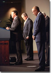 President George W. Bush bows his head as Rep. J.C. Watts, Jr. (R.-Okla.) leads a prayer before the swearing-in ceremony for Rod Paige, right, as Secretary of Education in the Barnard Auditorium at the Department of Education Jan. 24, 2001. White House photo by Eric Draper