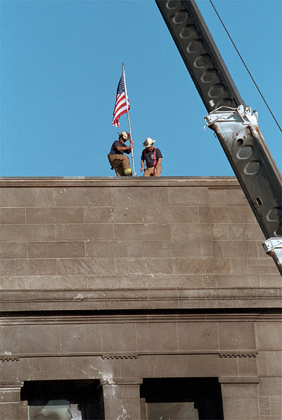 Echoing the actions of the soldiers who raised the flag in victory at Iwo Jima during World War II, firefighters post the American Flag directly into the scarred stone of the Pentagon Sept. 12. White House photo by Paul Morse.